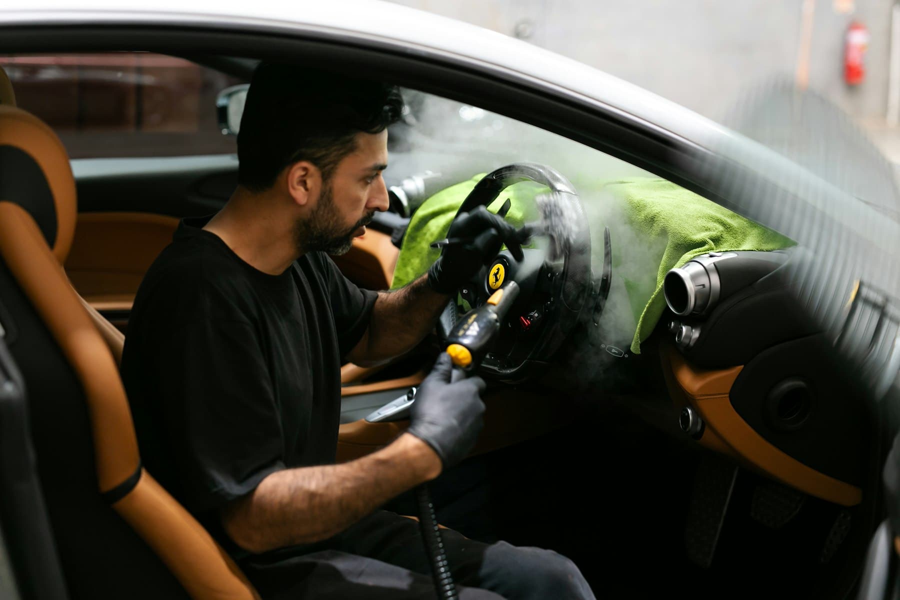 Steam cleaning a vehicle interior surface during a mobile car cleaning appointment